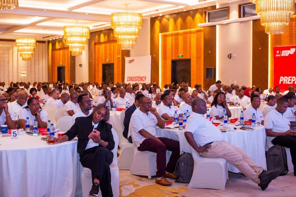 Conference audience in white Airtel shirts seated at round tables during Airtel StepUp