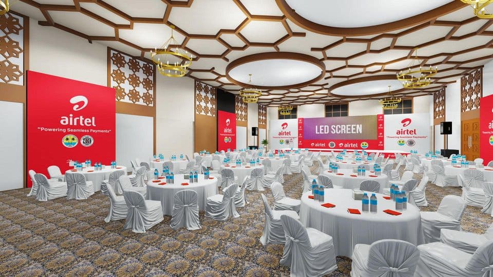 Visualization of a banquet hall set for Airtel’s Powering Seamless Payments event, with an LED screen and red Airtel branding